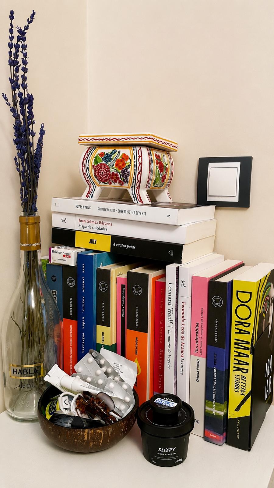 Estantería con libros, flores y un objeto decorativo sobre ellos